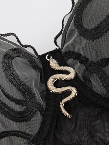 Close-up of snake charm on black lace mesh corset top with intricate embroidery detail
