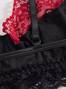 Close-up of red floral lace with black adjustable straps on skull print lingerie