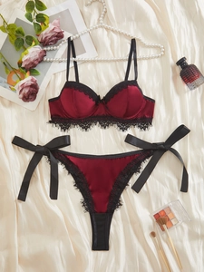 Dettaglio del set lingerie in raso bordeaux con pizzo nero e fiocchi laterali