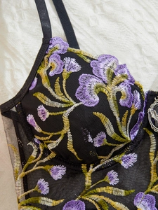 Close-up of floral embroidery on black mesh corset with vintage decorative buckle