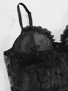 Détail d'un body en dentelle noire avec broderie florale et bretelles