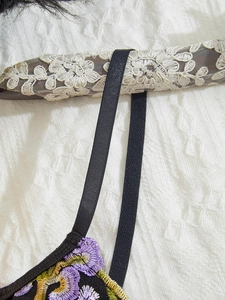 Close-up of elegant floral embroidery detail on a black mesh bustier corset top