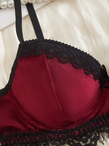Dettaglio reggiseno in velluto rosso vino con pizzo floreale nero e seta lucida
