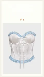 Detail of white corset top with blue floral lace trim and delicate white bow decoration