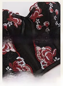 Close-up of floral embroidery on black mesh corset with silk bow detail