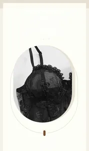 Détail d'un caraco en maille noire avec broderie rose et bordures en dentelle fine