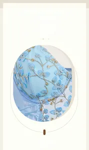 Detail of floral embroidery on light blue mesh lingerie with delicate gold thread accents