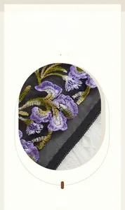 Detailed macro view of purple floral embroidery on sheer black mesh lace with scalloped edges
