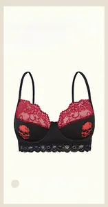 Detailed view of black silk bra featuring red lace trim and central skull print