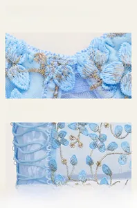Detailed view of sky blue floral embroidery on sheer mesh fabric with side lace-up ties