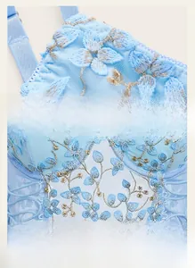 Detail of light blue lace bra featuring floral embroidery with gold thread and sheer mesh
