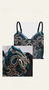 Detailed embroidery view of black corset top with blue floral patterns and cross pendant