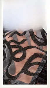 Macro detail of the breathable black mesh fabric and intricate spiral floral embroidery
