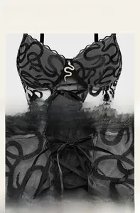 Close-up of black mesh corset with snake embroidery and metallic pendant detail