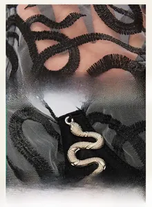 Detailed macro shot of black lace mesh fabric and silver snake pendant on corset top