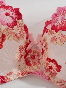 Close-up of floral embroidery on pink mesh lingerie set with a satin bow detail