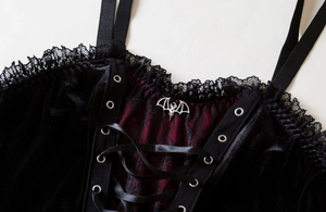 Detail of gothic velvet corset top featuring lace trim and silver bat pendant