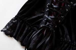 Close-up detail of gothic corset top featuring black velvet fabric and lace trim with lacing