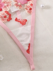 Close-up of floral embroidery on pink sheer mesh lingerie with elegant pearls