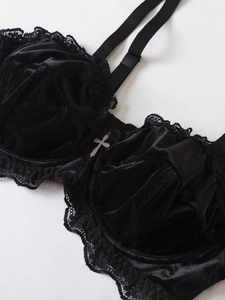 Detail of black velvet bra with lace trim and silver cross pendant in gothic style