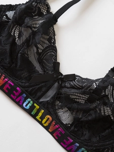 Detail of black floral lace bra featuring rainbow LOVE elastic band and satin bow