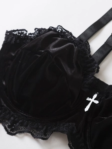 Detailed macro view of black velvet bra with eyelash lace trim and silver cross pendant
