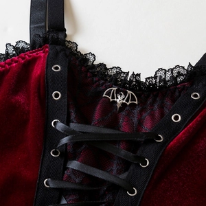 Macro shot of burgundy velvet corset with black lace trim and silver bat charm detail
