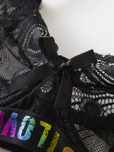 Detail of black lace lingerie set with satin bow and rainbow metallic letter waistband
