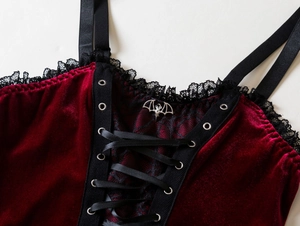 Detail of red velvet corset top with black lace trim and silver bat buckle detail