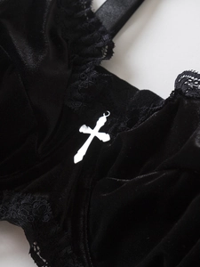 Close-up of black velvet bra with delicate lace trim and a silver cross pendant detail
