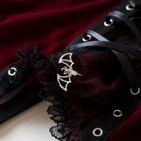 Detail of gothic velvet corset featuring lace trim and silver bat pendant