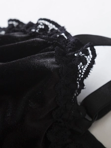 Close-up of black velvet fabric with intricate floral lace trim and satin texture details