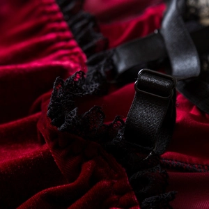 Close-up of burgundy velvet fabric with delicate black lace trim and adjustable strap