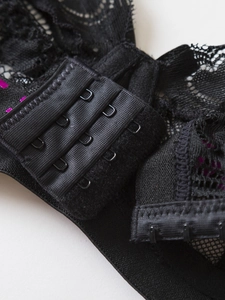 Detail showing the three-row hook-and-eye closure on a black lace bra with satin finish