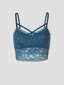 Close-up of peacock blue lace bralette featuring delicate floral patterns and cross straps