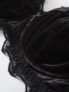Close-up of black velvet bra with lace trim and a silver cross pendant detail