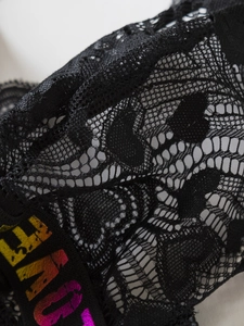 Détail de la dentelle florale noire et de l'imprimé lettres arc-en-ciel sur les bretelles