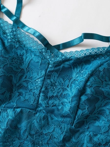Detailed close-up of peacock blue lace fabric with floral patterns and satin shoulder strap