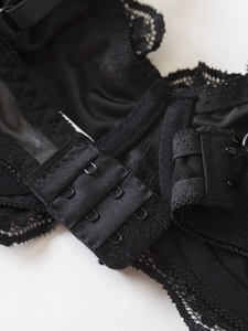 Detail of adjustable triple hook-and-eye back closure on black lace lingerie bra
