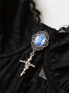 Detail of gothic lace corset featuring a blue gemstone and a vintage silver cross pendant