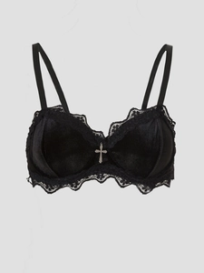 Detail of gothic black velvet bra with delicate lace trim and metal cross pendant