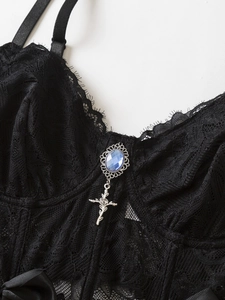 Detailed lace texture with a blue gemstone and silver rose cross pendant on a black corset