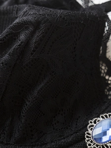 Detail of floral black lace fabric with a vintage blue gemstone and silver metal filigree