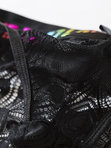 Close-up of black floral lace fabric with colorful rainbow prints and leather-like trim