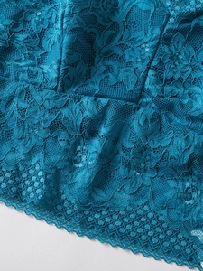 Detail shot of delicate peacock blue floral lace embroidery on a sheer mesh camisole top