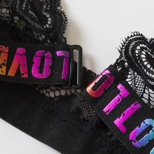 Détail d'une brassière en dentelle noire avec bretelles à lettres LOVE colorées
