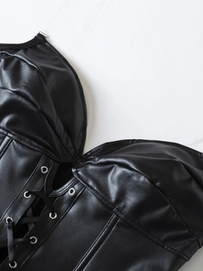Detail of black faux leather corset featuring lace-up front with metal eyelets