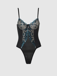 Détail macro du body en dentelle noire avec broderie florale bleue et dorée