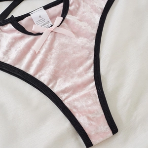 Dessous-Set aus rosa Samt mit schwarzen Kontrastkanten und Satinschleife auf Stoffhintergrund