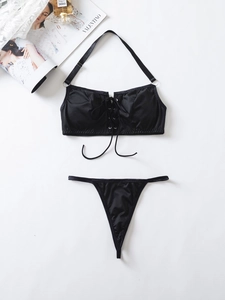 Detail of black satin lingerie set with halter neck ties and cross-strap design